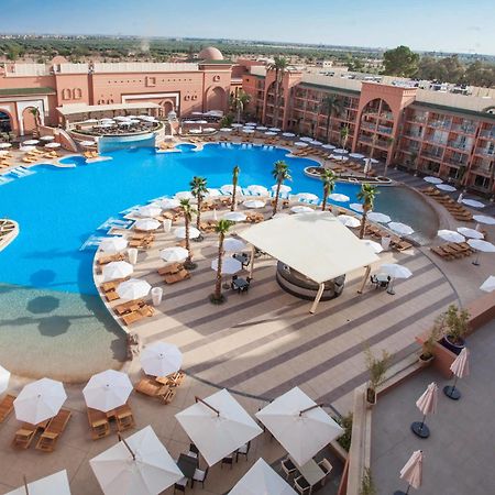 Savoy Le Grand Hotel Marrakech Marrakesh Exterior foto The photo shows a large, luxurious hotel resort with a spacious swimming pool at its center. The pool area features several lounge chairs and umbrellas arranged around the water, providing a relaxing atmosphere for guests. Surrounding the pool are la