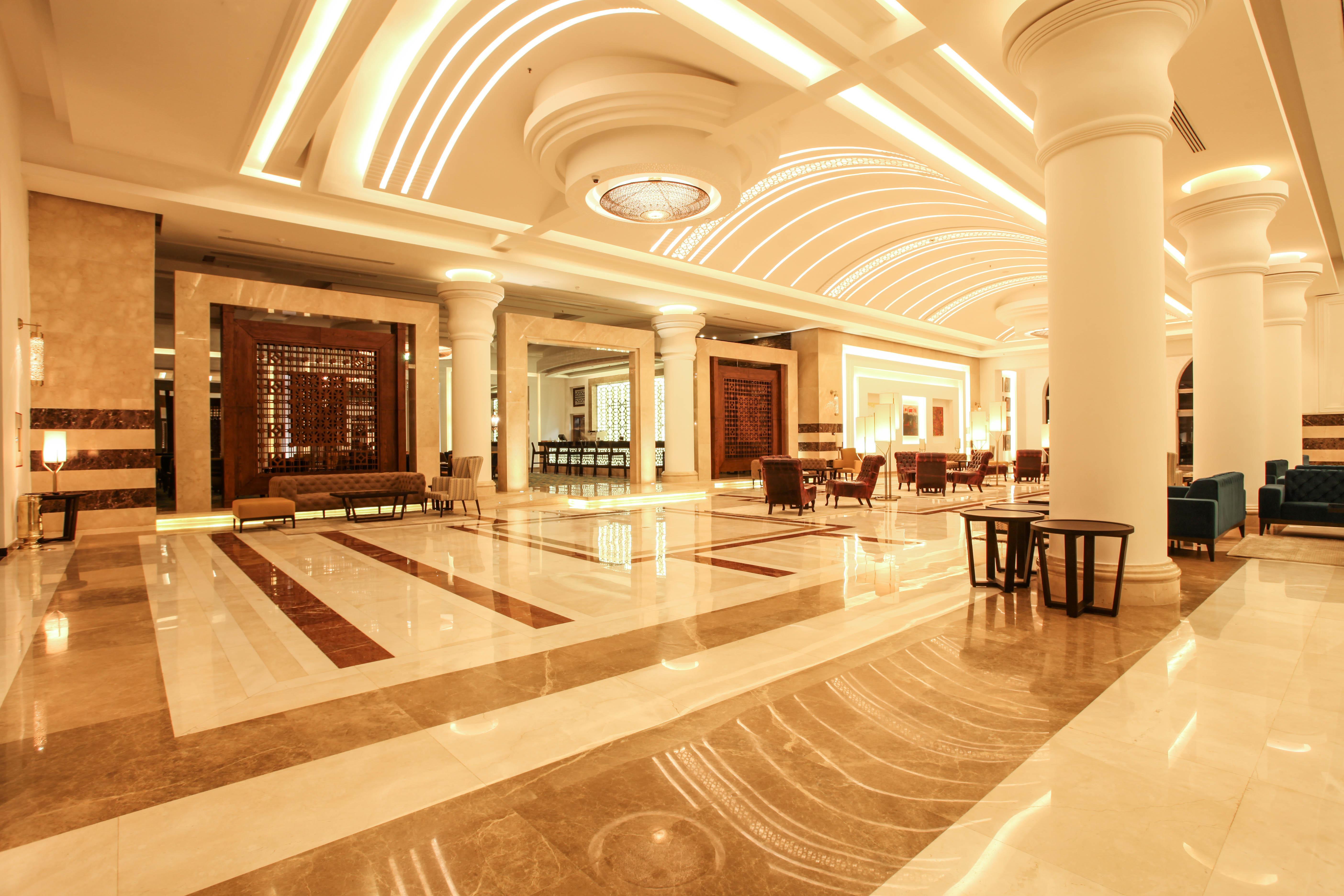 Savoy Le Grand Hotel Marrakech Marrakesh Exterior foto The photo shows an elegant hotel lobby with a spacious and luxurious design. The floor features a mix of light and dark marble patterns, creating an appealing visual contrast. The ceiling has a modern, curved design with soft lighting that enhances t