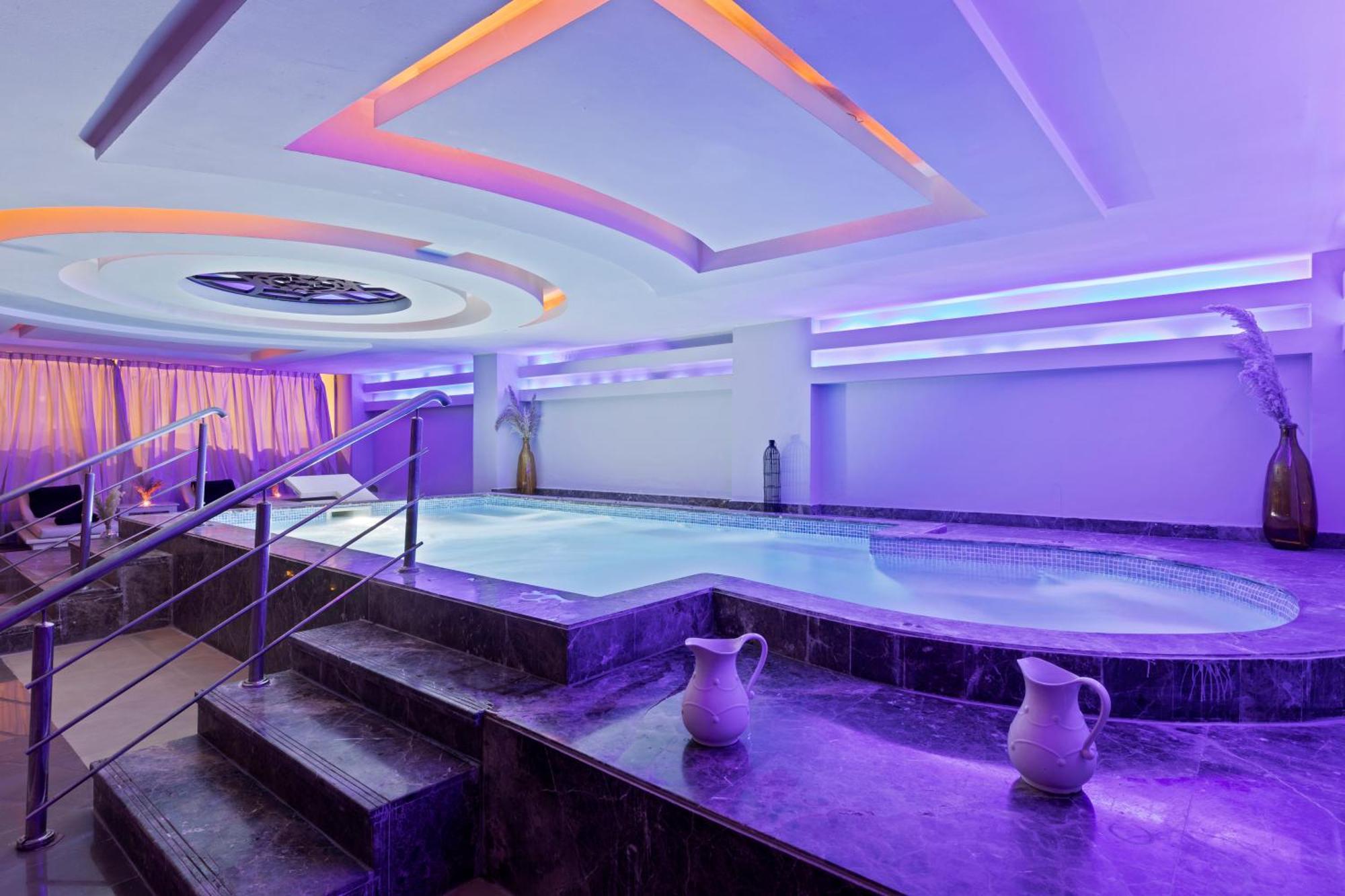 Savoy Le Grand Hotel Marrakech Marrakesh Exterior foto The photo shows a modern spa area featuring a small indoor pool or hot tub. The space is illuminated with soft purple and blue lighting, creating a calming ambiance. There are decorative features on the ceiling, and the walls are lined with soft curt